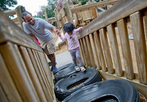 Shiva Arjunon (left) helps his daughter Sasha Kumar up a ramp made of tires at the Wacky World Playground at Wills Park in Alpharetta on Thursday, August 8, 2013. 