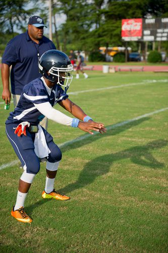 Cedar Grove's James Hartsfield (front) waits for the ball to be hiked as coach Lawrence Smith watches during warmups before their game against Tucker at Panthersville Stadium in Decatur on Friday, August 23, 2013.  