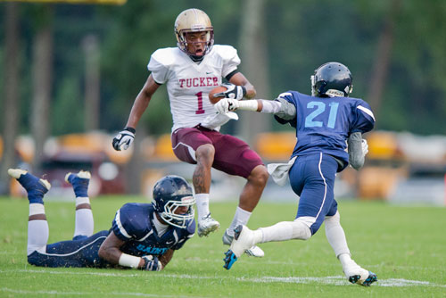 Tucker's Dominick Sanders (1) jumps over Cedar Grove's Labron Morris Jr. (left)  as D'Angelo Pinkett (21) closes in during their game at Panthersville Stadium in Decatur on Friday, August 23, 2013. 