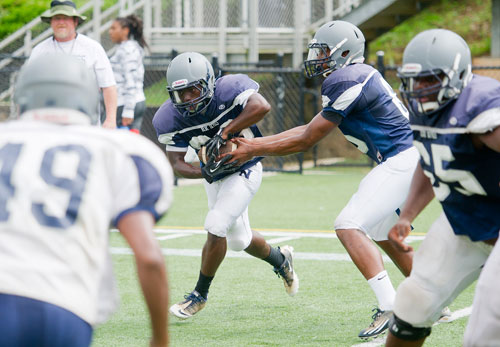 Norcross' Kadarius Garrett (center) is handed the ball by A.J. Bush (right) during practice on Wednesday, August 21, 2013. 