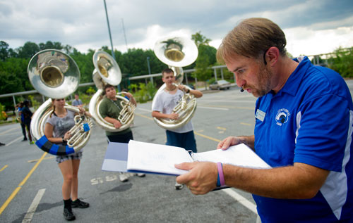 Band director Michael Reid (right) looks over his positioning chart as Tiffany Apple (left), Louis Deoliveira and Corey Payne wait to be placed during marching band practice at Centennial High School in Roswell on Thursday, August 22, 2013. 