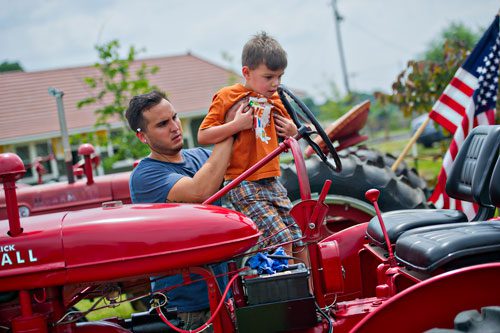 Daniel Moore (left) lifts his nephew Logan Haney onto a 1941 Farmall B tractor during Trains, Trucks and Tractors at the Southeastern Railway Museum in Duluth on Saturday, August 3, 2013. 