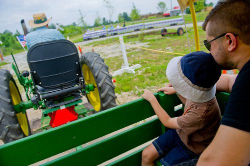 Max Eremine (right) and his son Henry take a tractor pulled hayride with Kim Kimbrell during Trains, Trucks and Tractors at the Southeastern Railway Museum in Duluth on Saturday, August 3, 2013. 