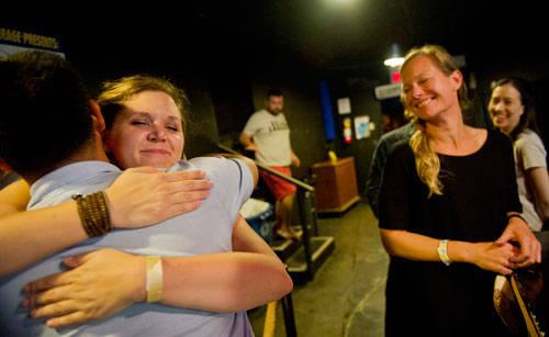 Sarah Ackerman (left) gives away a "free hug" to Andrew Chang as Jennifer Holbach watches during the Bringing Down the House Party at Dad's Garage in Atlanta on Saturday, August 3, 2013.