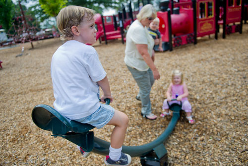 Keen Hendrix (left) rises into the air on a see saw as he plays with Natalie Wilson, her brother Porter and grandmother Nancy O'Connell on the train shaped playground at Thrasher Park in Norcross on Thursday, August 8, 2013. 