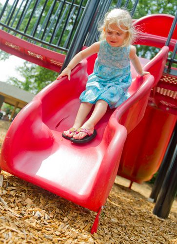 Hailey Cook zooms down a slide at the playground at Thrasher Park in Norcross on Thursday, August 8, 2013.