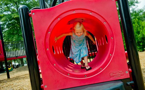 Hailey Cook climbs through a tunnel at the playground at Thrasher Park in Norcross on Thursday, August 8, 2013.
