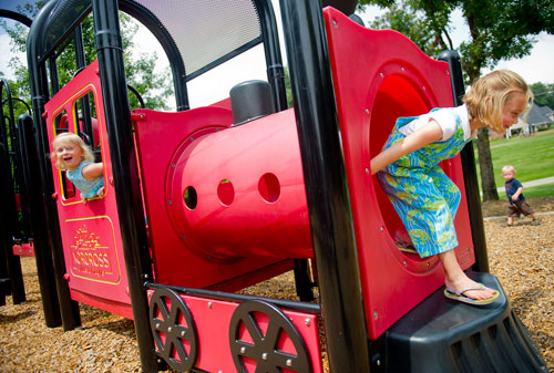 Virginia Cook (right) and her sister Hailey play on the train shaped playground at Thrasher Park in Norcross on Thursday, August 8, 2013. 