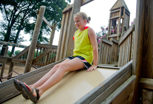 Maggie Coyle zooms down one of the slides at the Wills Park Playground in Alpharetta on Thursday, August 8, 2013.