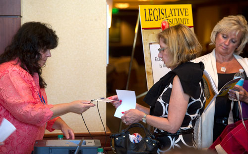 Joanne Stroud (left) hands Robyn Gael her badge as Sindy Ramsey waits in line to register for the 2013 National Conference of State Legislators at the Omni Hotel in Atlanta on Sunday, August 11, 2013. 5,000 attendees are expected at the conderence this year including around 1,000 state legislators from all over the nation.