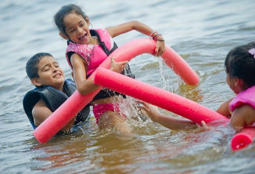 Rodrigo Hernandez (left) lifts his sister Michelle into the air as they swim in Lake Lanier at Van Pugh Park in Flowery Branch on Sunday, September 1, 2013. 
