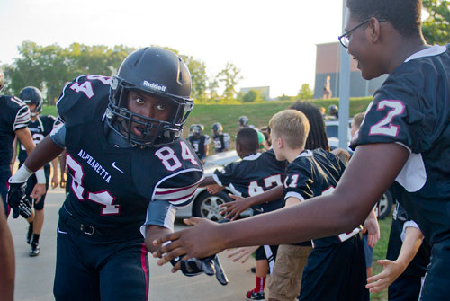 Alpharetta's Chris Thomas (84) gives a high five to Junior Uzebu (72) as he walks towards the field before their game against Lovejoy on Friday, September 13, 2013.