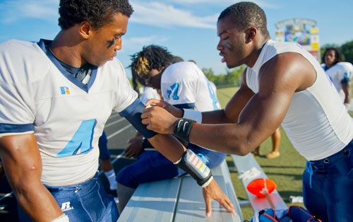 Lovejoy's Kevin Morris (left) has help taping up his elbow from Dante Atkins (right) before their game against Alpharetta on Friday, September 13, 2013. 