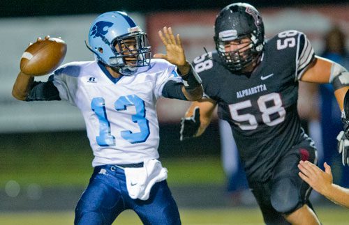 Lovejoy's Quintarius Neely (13)  tries to find an open receiver as Alpharetta's Andrew Butcher (58) closes in on Friday, September 13, 2013. 