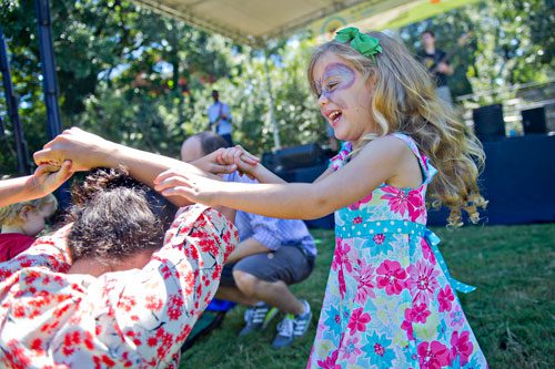 Tegan Derro (right) is spun by Kristina Garcia as she dances in front of the stage during the Reynoldstown Wheelbarrow Festival at Lang Carson Park in Atlanta on Saturday, September 14, 2013.