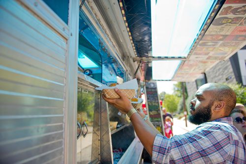 Jonathan Dossman (right) grabs his order from the Mixd-Up food truck during the Reynoldstown Wheelbarrow Festival at Lang Carson Park in Atlanta on Saturday, September 14, 2013. 