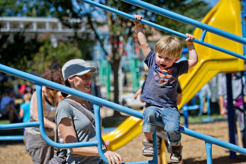 Liam Talton-Buck (right) hangs on the playground as his mother Betsy watches him play during the Reynoldstown Wheelbarrow Festival at Lang Carson Park in Atlanta on Saturday, September 14, 2013. 