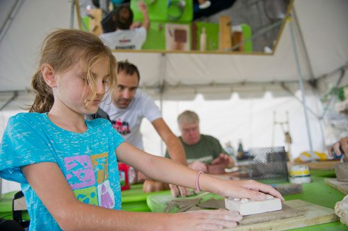 Mia Bergin (left), her father Mike and artist Bill Buckner work with clay at the Creation Station during the Atlanta Arts Festival at Piedmont Park on Sunday, September 15, 2013.