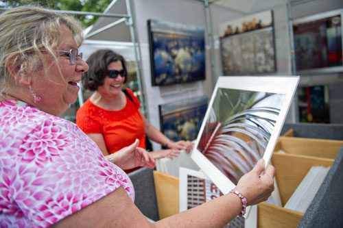 Laurie Fulton (left) and Susan Dumiak look at the photographs on display in Nathan Bailey's booth during the Atlanta Arts Festival at Piedmont Park on Sunday, September 15, 2013. 