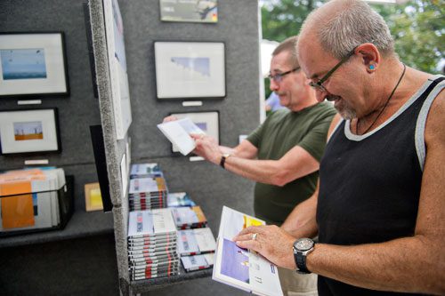 Alan Lancaster (right) and Rob Lee look at the illustrations in artist Greg Stones' new book during the Atlanta Arts Festival at Piedmont Park on Sunday, September 15, 2013. 