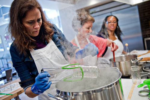 Kristin Stockton (left) pulls a mason jar from a pot of boiling water as Martha McMillin and Morgan Dooley prepare to can pear preserves during a canning class at The Preserving Place in Atlanta on Saturday, September 14, 2013.