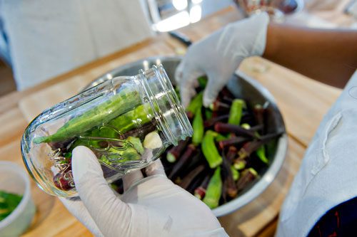Morgan Dooley stuffs a mason jar with okra at The Preserving Place in Atlanta on Saturday, September 14, 2013. 