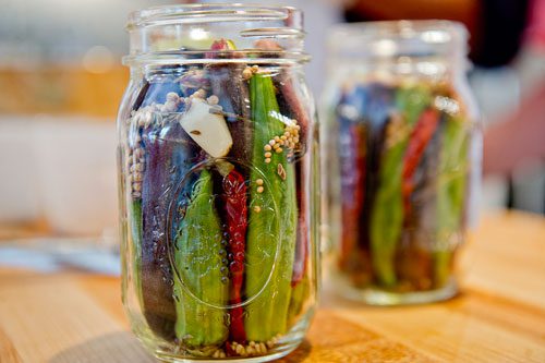 Glass mason jars filled with okra, garlic, red peppers and spices sit ready to be sealed at The Preserving Place in Atlanta on Saturday, September 14, 2013. 