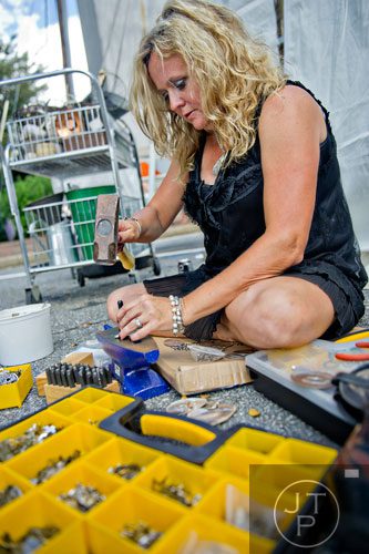 Tammy McHenry uses an anvil and hammer to hand stamp spoons during the European Market on Milton Street in Alpharetta on Sunday, September 22, 2013. 