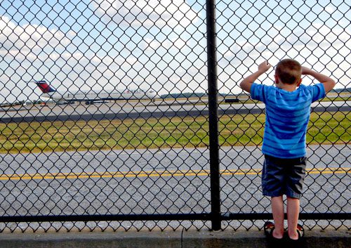 A young boy watches planes taxi down the runway at Hartsfield Jackson International Airport in Atlanta as he waits for his father to come home on Friday, September 20, 2013.