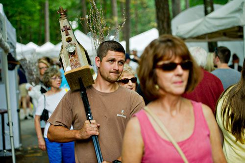 Ricky Cencula (left) carries a birdhouse as he walks one of the many vendor-lined paths during the Yellow Daisy Festival at Stone Mountain Park on Saturday, September 7, 2013. 