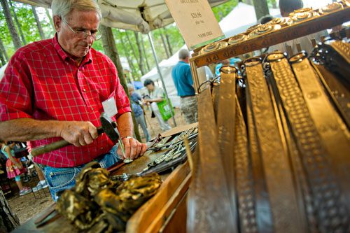Norris Crawford stamps a customer's name into a leather belt during the Yellow Daisy Festival at Stone Mountain Park on Saturday, September 7, 2013. 
