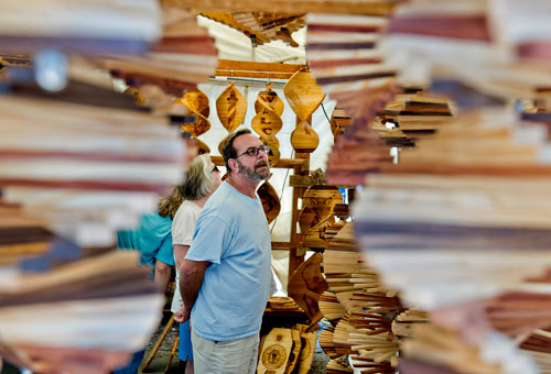 Jack Jones (center) looks at the wooden art on display at the Windworks Plants & Crafts booth during the Yellow Daisy Festival at Stone Mountain Park on Saturday, September 7, 2013. 