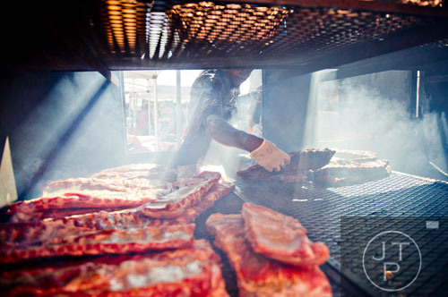Corey Sutton places a rack of spare ribs into his smoker during the Atlanta Bar-B-Q Festival at Atlantic Station in Midtown on Saturday, September 14, 2013. 