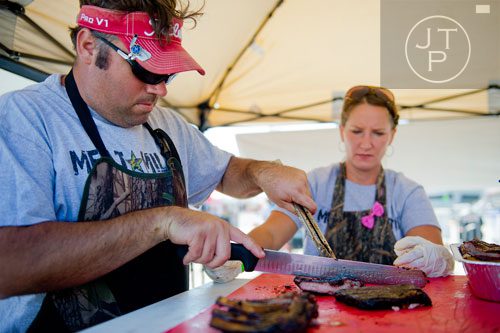 Andy Brent (left) with the Meat Militia team cuts a rack of spare ribs as his wife Jana searches for the best ones during the Atlanta Bar-B-Q Festival at Atlantic Station in Midtown on Saturday, September 14, 2013. 
