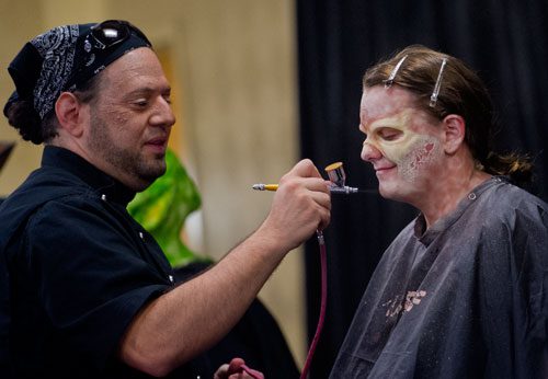 R.J. Haddy, one of the contestants on the SyFy Channel's FaceOff reality television show, airbrushes Emily Allen's face during DragonCon in downtown Atlanta on Saturday, August 31, 2013.