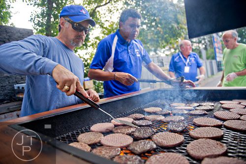 Casey Sullivan (left) and Eddie Goodlett flip burgers on the grill as they cook hamburgers before Walton takes on Lassiter at Walton HIgh School in Marietta on Friday, October 4, 2013.  