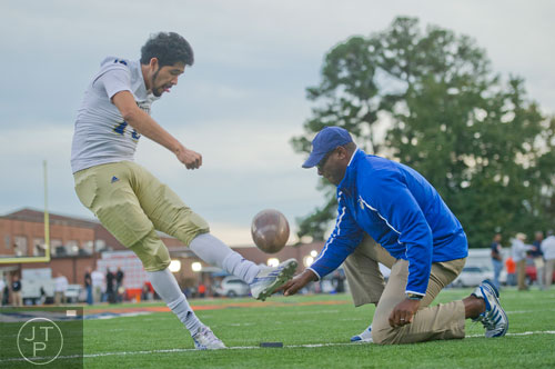 McEachern's Dennis Dominguez (16) kicks the ball as he practices his field goals with coach Sheddrick Wilson before their game against North Cobb on Friday, October 18, 2013. 