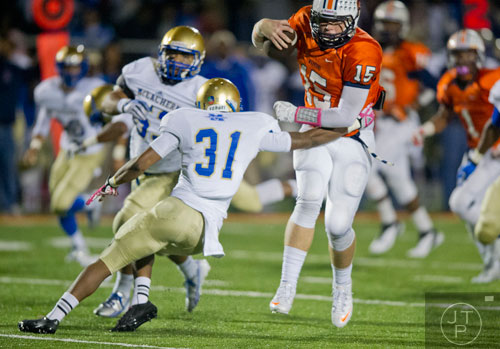 North Cobb's quarterback Tyler Queen (15) breaks a tackle by McEachern's Rahmoi Parsons (31) on Friday, October 18, 2013. 