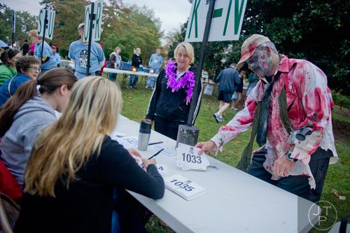 Carl Kriigel (right) picks up his bib number for the 2013 Run Like Hell 5k at Oakland Cemetery in Atlanta on Saturday, October 19, 2013.