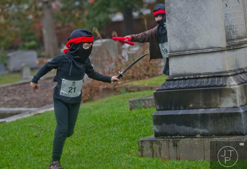 Ryan Jones (left) is chased around a gravestone by Nolan Chiles before the start 2013 Run Like Hell 5k at Oakland Cemetery in Atlanta on Saturday, October 19, 2013. 