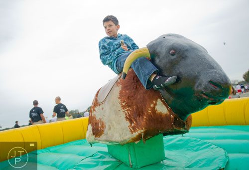 Isaiah Scott holds on as he is thrown about on top of a mechanical bull before the start of the Great Bull Run at the Georgia International Horse Park in Conyers on Saturday, October 19, 2013.