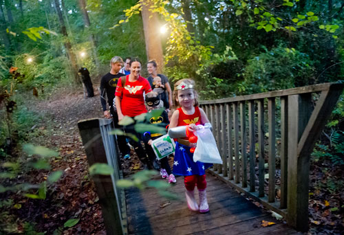 Caroline Roberts (right) and Bella Lotz lead their families over a bridge as they walk the trails at the Chatthoochee Nature Center in Roswell during a Halloween Hike on Saturday, October 19, 2013. 