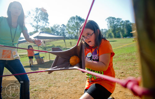 Lauren Winters (right) pulls back on a pumpkin slingshot as Tiffany Peacock leans in to help at the Still Family Farm in Powder Springs on Saturday, October 5, 2013. 