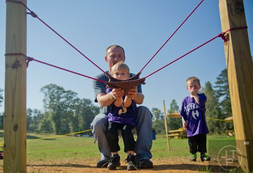 Jason Tarpley helps his son Ary aim the pumpkin slingshot as his other son Caiden watches at the Still Family Farm in Powder Springs on Saturday, October 5, 2013.