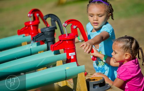 Nya Parker (right) and her sister Nahla crank the water pumps at the rubber duck race station at the Still Family Farm in Powder Springs on Saturday, October 5, 2013.