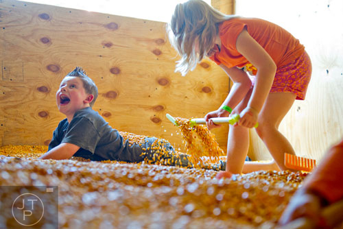 Zoe Odum covers her brother Ty in kernels of corn at the Buford Corn Maze on Saturday, October 5, 2013.