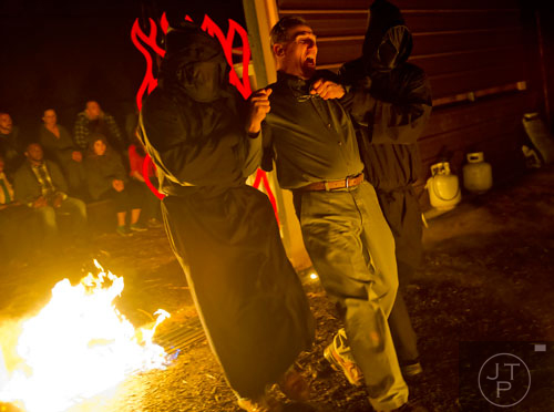 Chris Dearwent (left) and Roger Jameson (right) lead Victor Dalton into the Lake of Fire during a scene in Hell's Gates at Lighthouse Baptist Church in Dawsonville on Thursday, October 17, 2013. 
