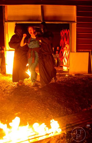 Sharon Smith (center) is led to the Lake of Fire by Chris Dearwent (left) and Roger Jameson during Hell's Gates at Lighthouse Baptist Church in Dawsonville on Thursday, October 17, 2013.