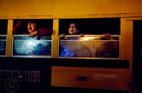 Jessica Gonzalez (left) and Leah Diemer scream from the windows of a school bus as groups make their way through Hell's Gates at Lighthouse Baptist Church in Dawsonville on Thursday, October 17, 2013.