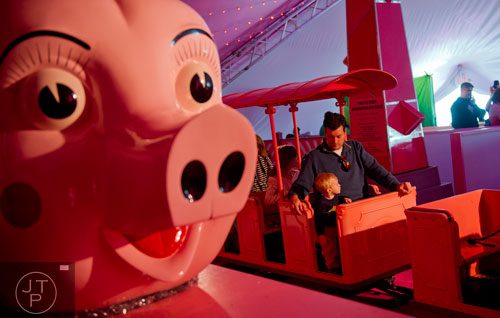 Emmett Holbert (left) sits next to his father Ryan as they ride the Macy's Pink Pig at Lenox Square Mall in Buckhead on Saturday, November 2, 2013.